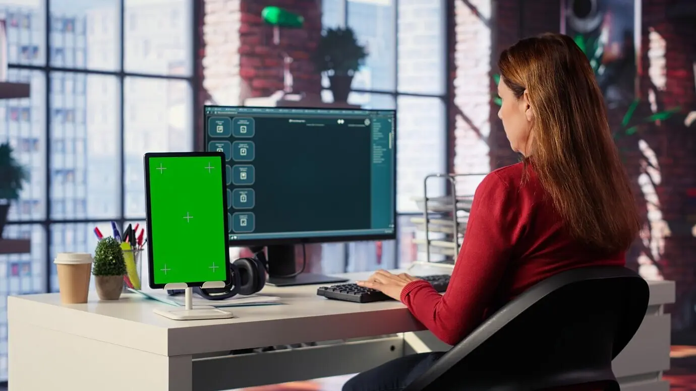 Freelancer, der neben einem Mockup-Bildschirm mit einem intelligenten virtuellen KI-Assistenten interagiert.